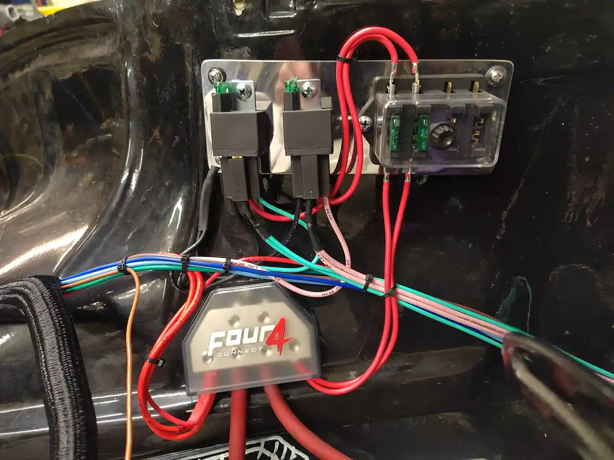 A close-up photo shows a car's interior wiring harness with multiple colored wires connected to black electrical connectors…