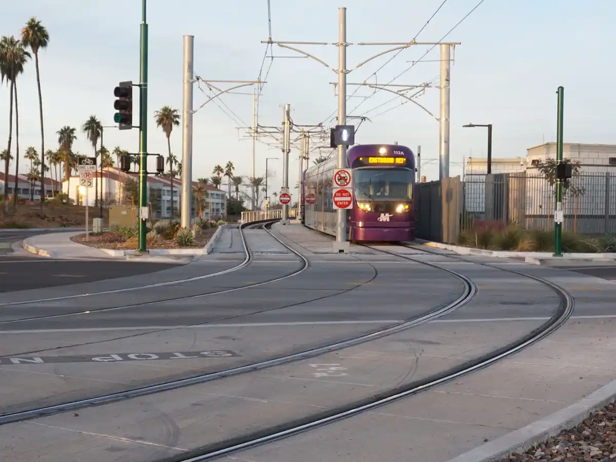 A purple light rail train labeled 'EASTBOUND MEX' approaches a curved track intersection with visible 'DO NOT ENTER' signs…