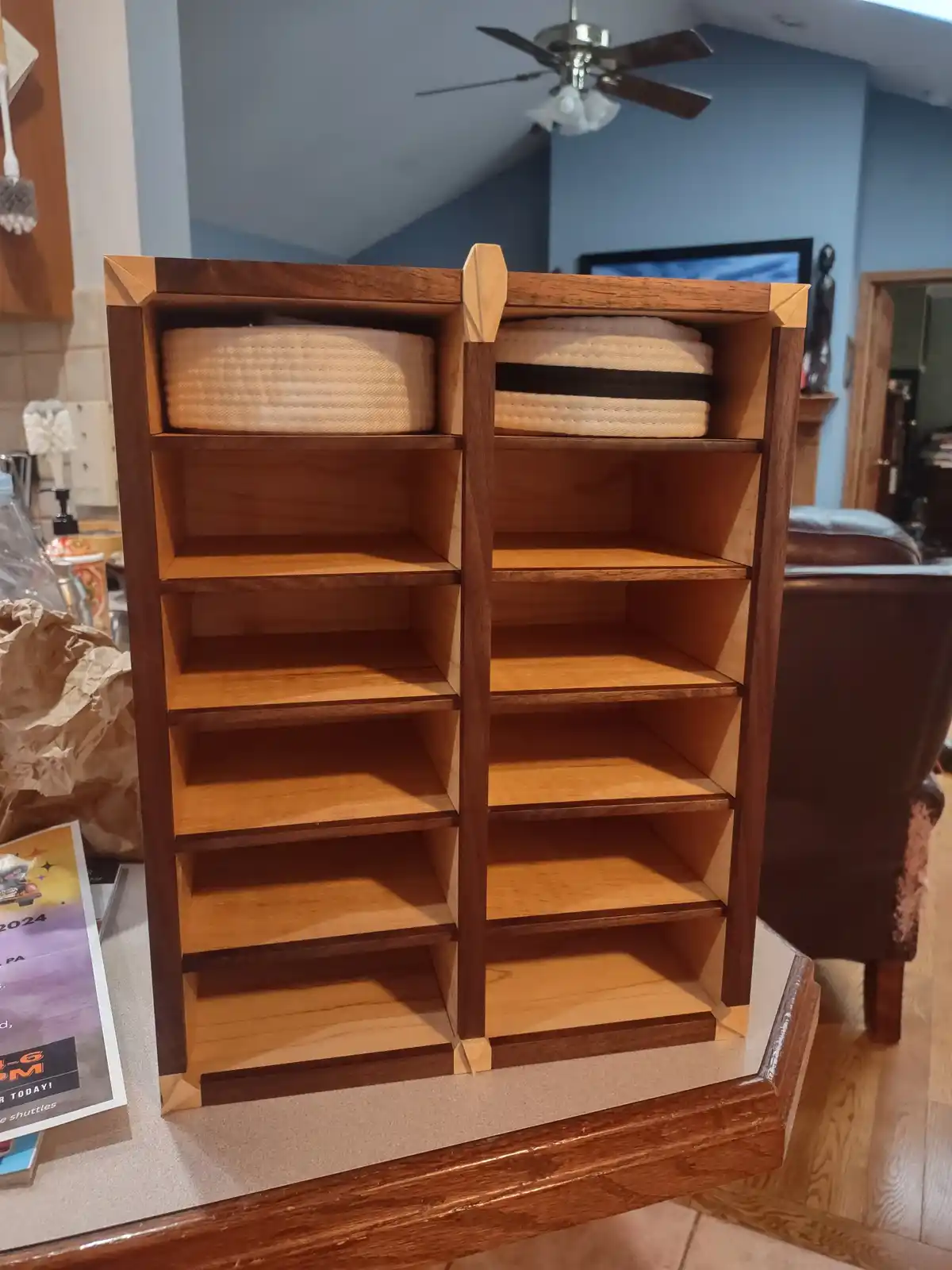 A wooden, two-column, eight-compartment shelf unit sits on a kitchen counter, with only the top two compartments holding…