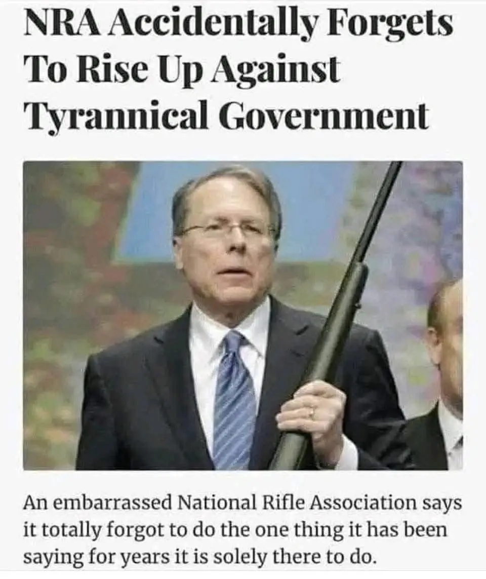 A man in a suit and glasses holds a rifle while looking upward, with overlaid text reading 'NRA Accidentally Forgets To Rise…