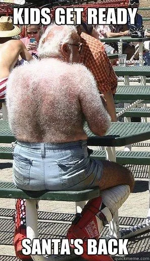 A man with a very hairy back is sitting on a green picnic bench outdoors, viewed from behind. He wears light blue denim…