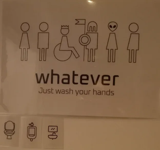 A bathroom sign displays a row of diverse stick figures including male, female, wheelchair user, person with a flag, alien…
