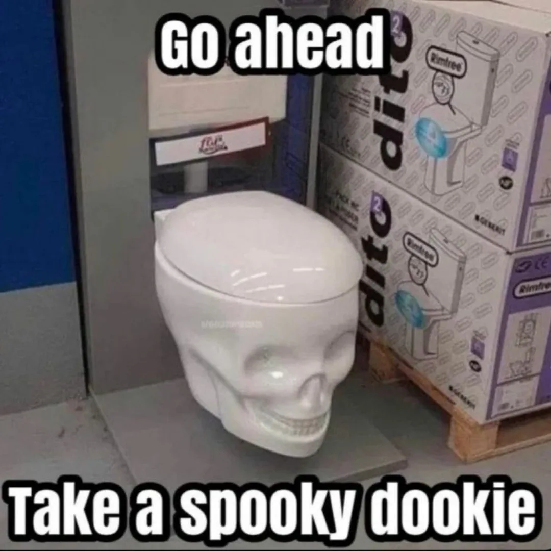A white ceramic toilet shaped like a human skull sits on a display stand in a warehouse, next to stacked boxes of 'Rimfree'…