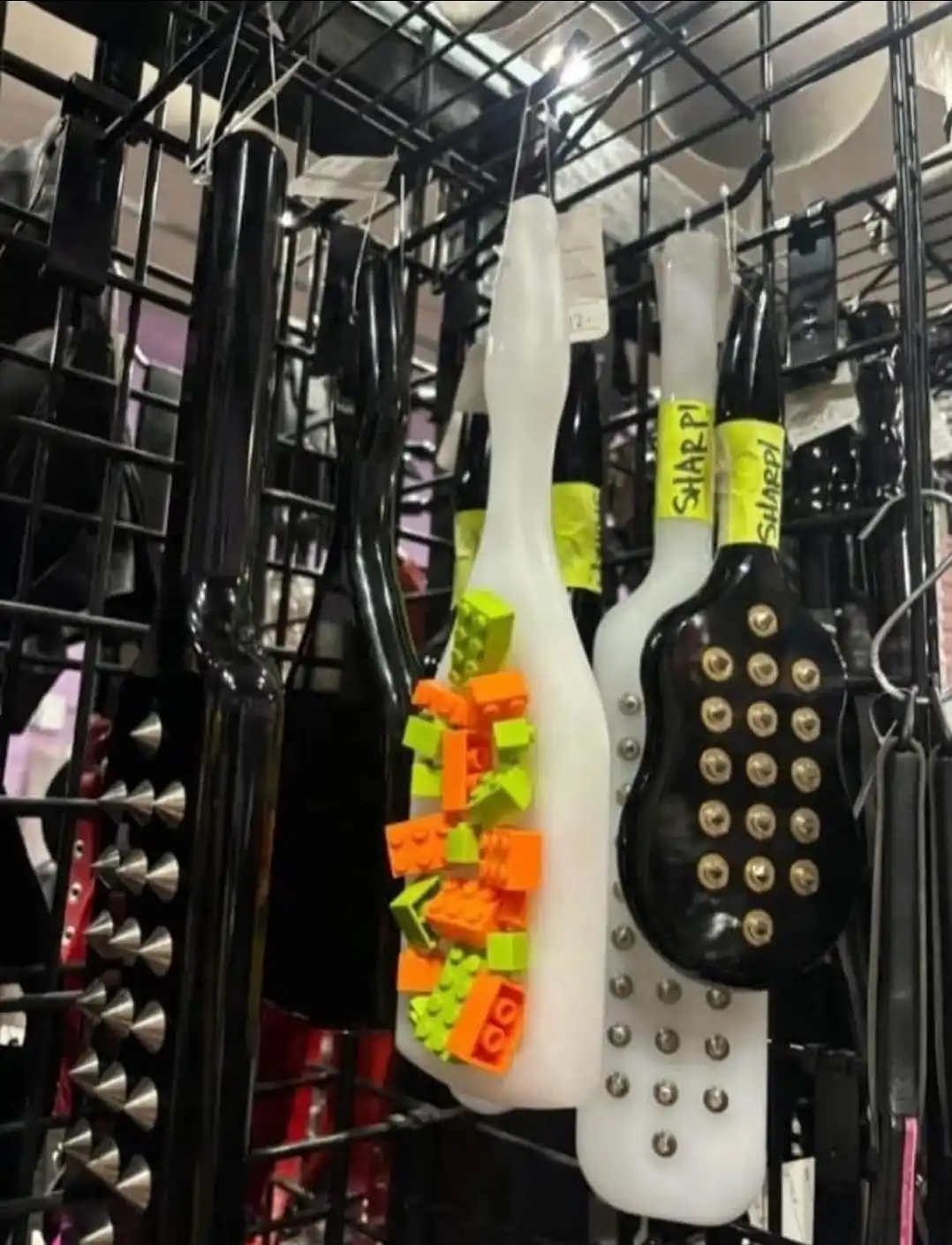 A photo shows several black and white plastic paddles hanging on a metal rack in what appears to be a store. One white…