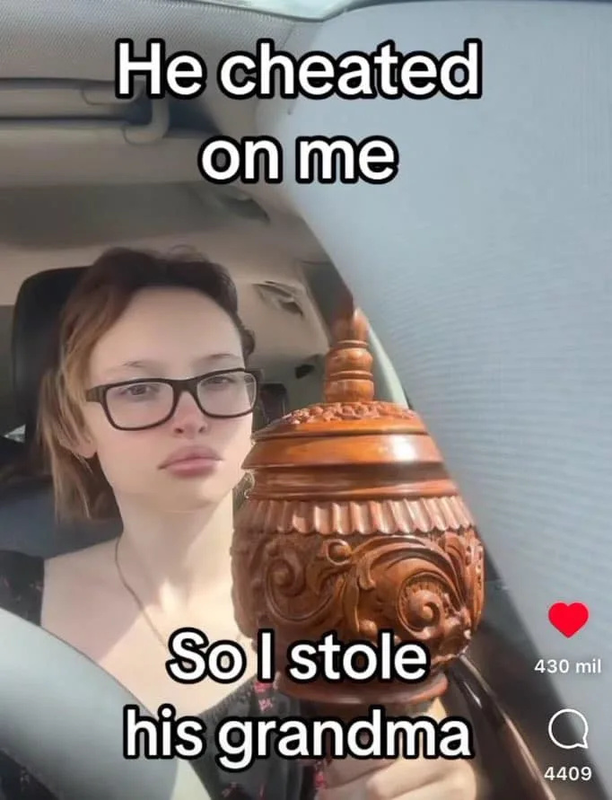 A woman wearing glasses sits in a car, holding a large, ornately carved wooden urn. Text overlaid on the image reads 'He…