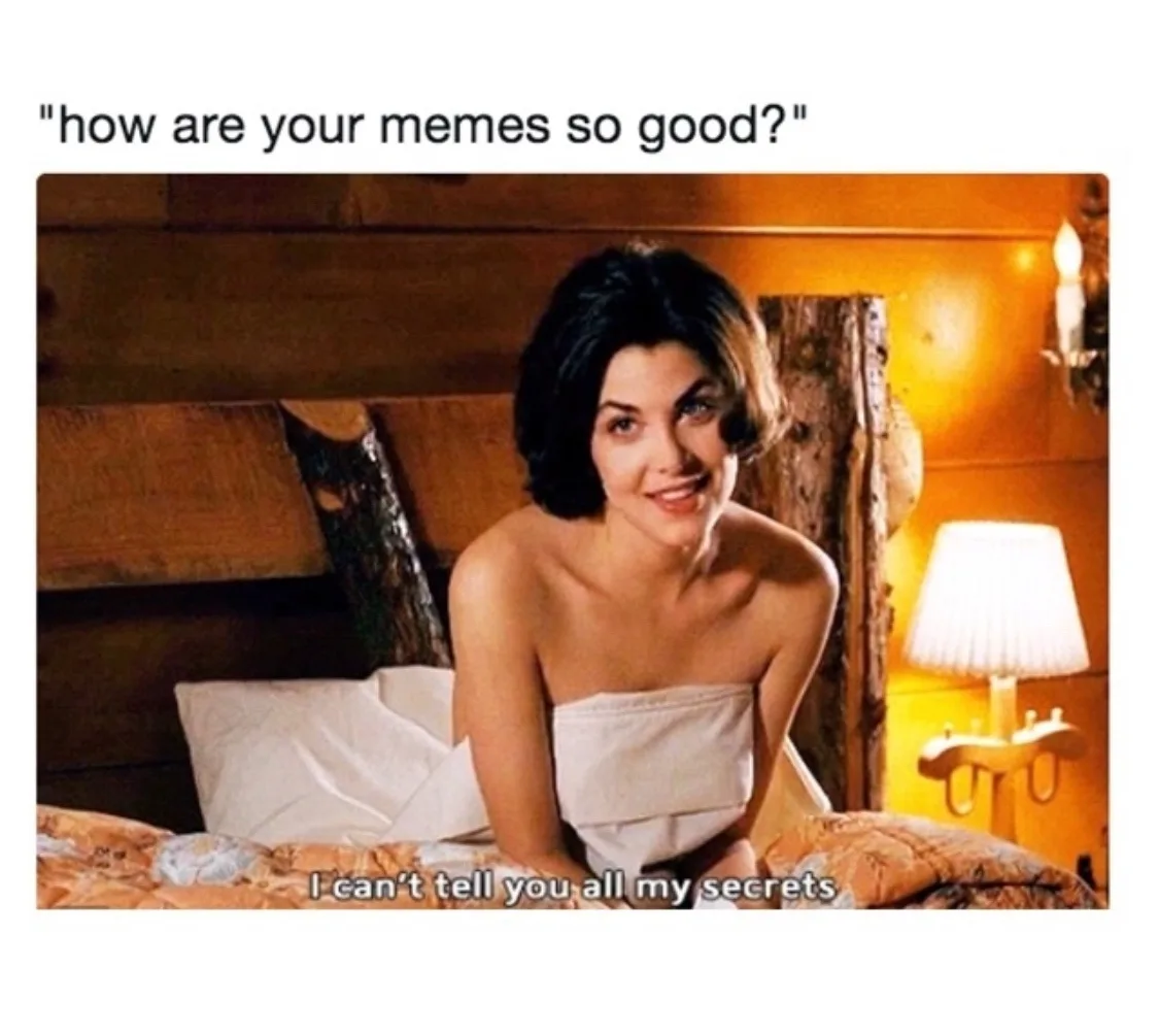 A woman with short dark hair, wrapped in a white towel, sits on a bed with a wooden headboard and a lit lamp nearby. The…