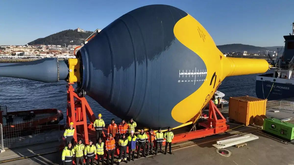 A group of workers in high-visibility vests and hard hats pose for a photo in front of a massive, uniquely shaped blue and…