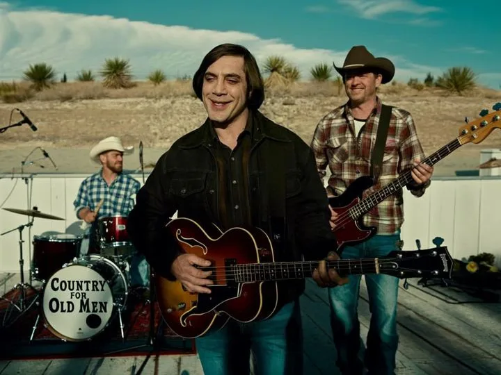 A band plays country music outdoors in a desert setting. The drummer's bass drum is clearly visible with the text 'COUNTRY…