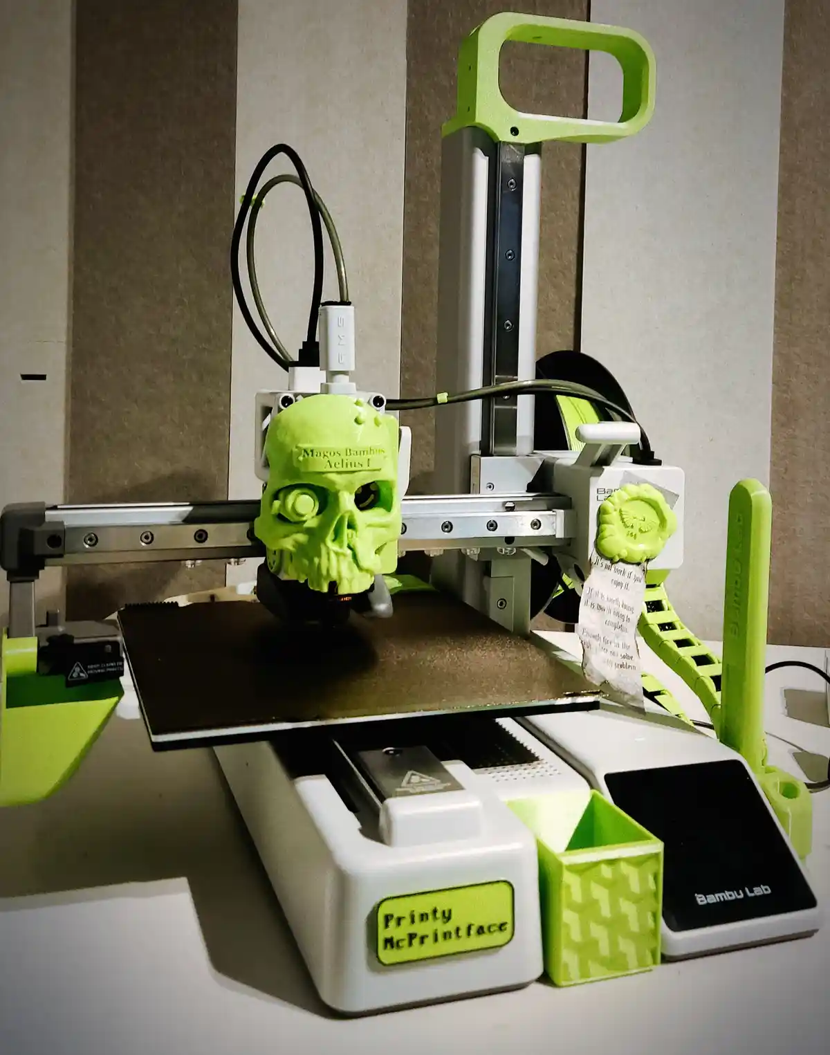 A lime-green 3D printer, branded 'Bambu Lab', is shown printing a matching lime-green skull. The skull has 'Magos Bambus…