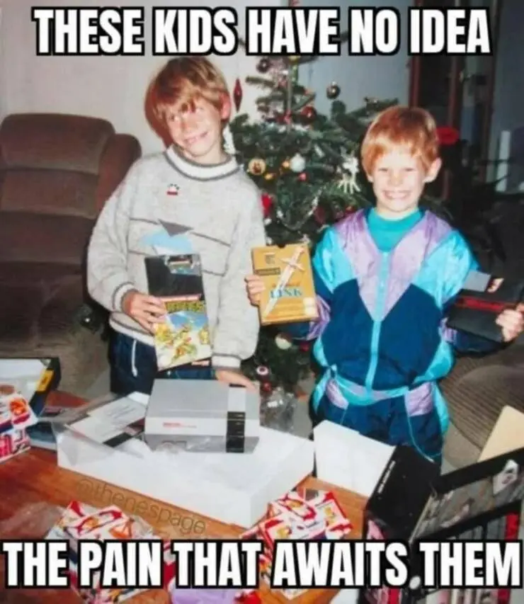 Two young boys in 1990s clothing stand in front of a decorated Christmas tree, each holding a video game cartridge. On the…