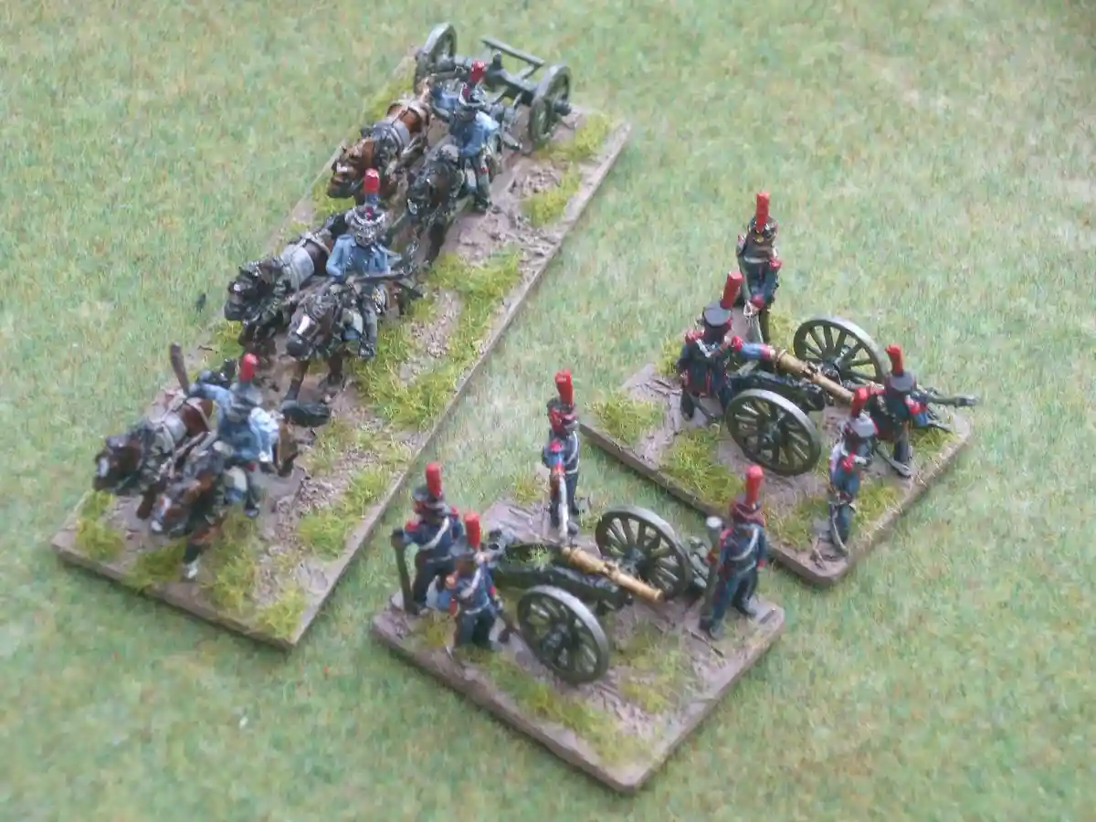 A photo of miniature wargaming figures shows a cavalry unit on horseback charging toward two stationary artillery units…