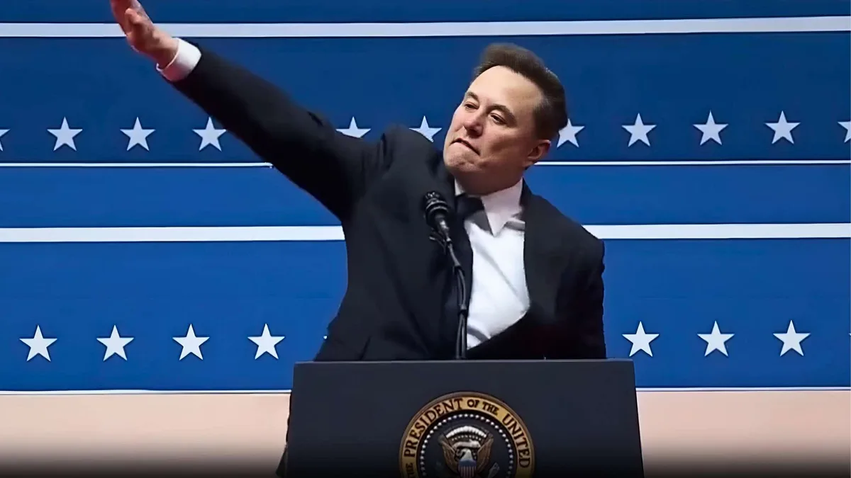 elon musk stands at a podium bearing the presidential seal, gesturing with his right arm raised against a blue backdrop with…