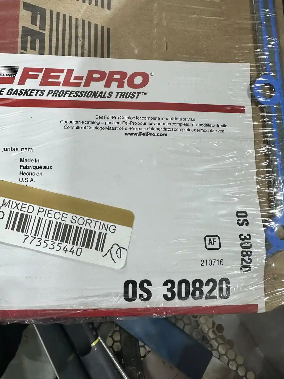 A close-up photo of a Fel-Pro gasket box wrapped in plastic, showing the brand logo, product code OS 30820, and a 'MIXED…