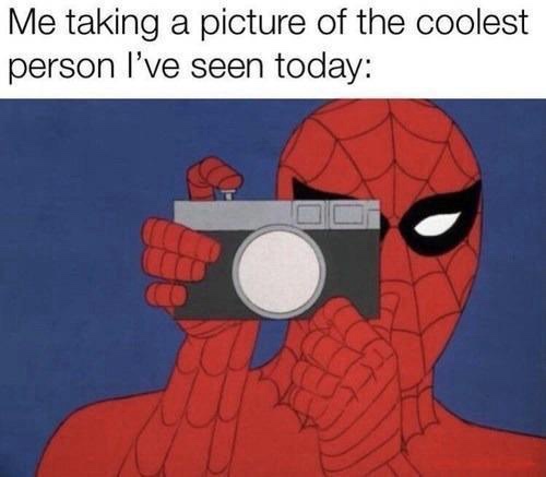 A cartoon depiction of Spider-Man holding a camera up to his face, obscuring his mouth and nose, as if taking a photo. The…