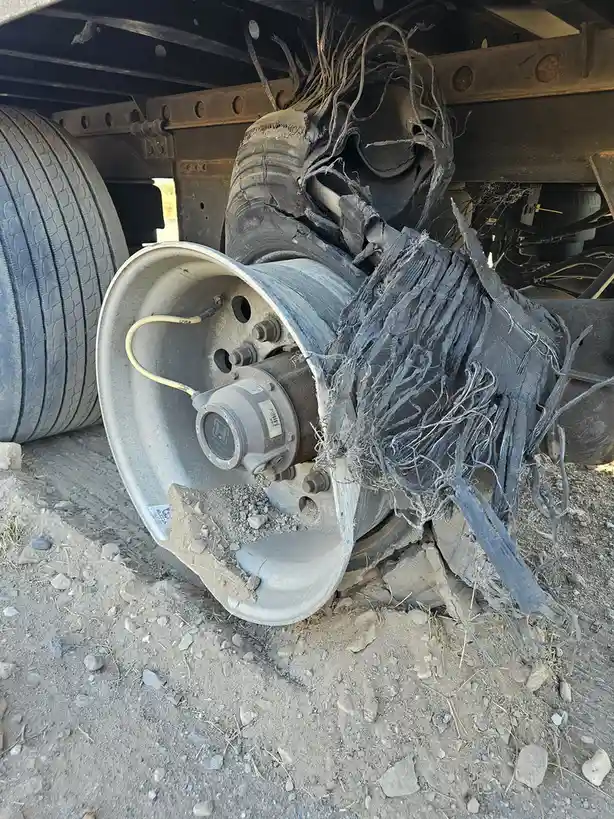 A close-up photo shows a severely damaged truck tire, with its rubber shredded into long, frayed strands resembling hair…