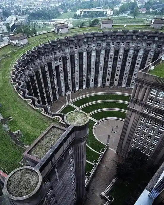an aerial view of the curved, multi-story concrete building known as the Congress Center in Dresden, Germany, which appears…
