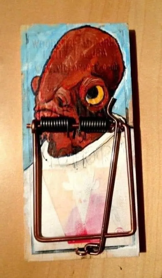 A painted portrait of a red-skinned, bald humanoid with a large yellow eye is affixed to a wooden surface and overlaid with…