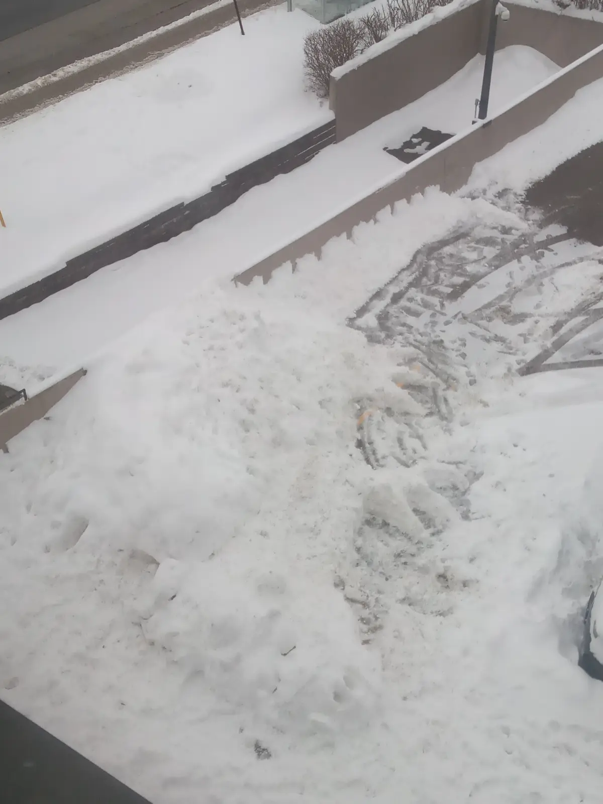 An aerial view of a snow-covered parking lot with a large pile of snow and tire tracks, overlaid with the text 'i'm not…