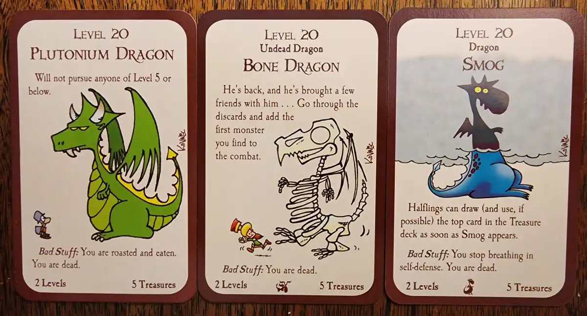 Three Level 20 dragon cards from a fantasy card game are displayed side-by-side on a wooden surface. The left card shows a…