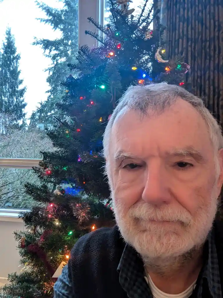 A close-up selfie of an older man with white hair and a beard, looking directly at the camera with a weary, resigned…