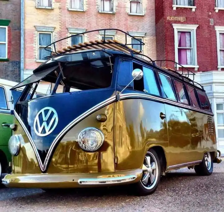 a vintage volkswagen type 2 bus with a glossy blue and gold two-tone paint job, featuring a pop-up windshield, chrome trim…
