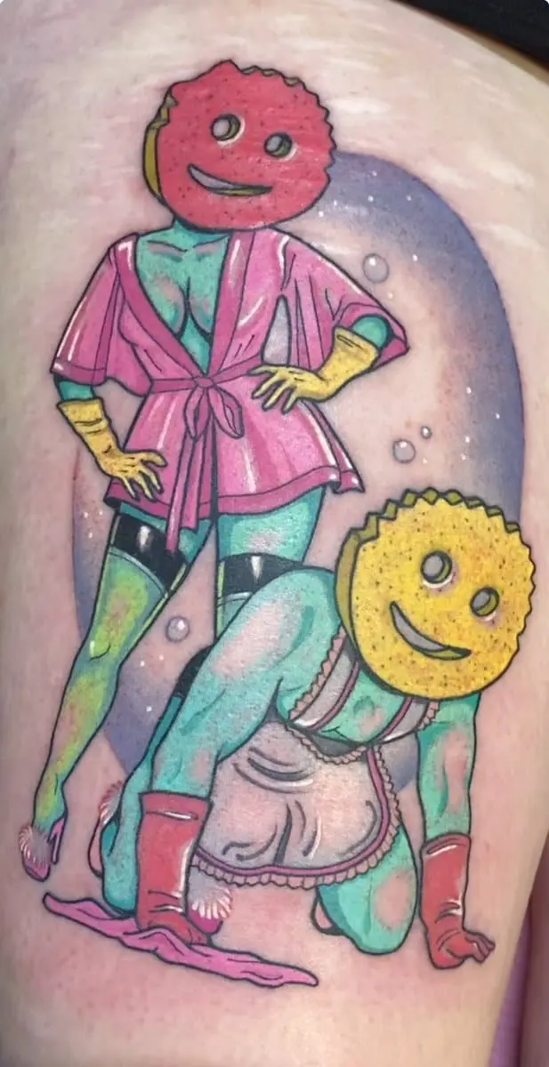 A tattoo on skin depicts two cartoon characters: one with a red, textured face wearing a pink robe and yellow gloves…