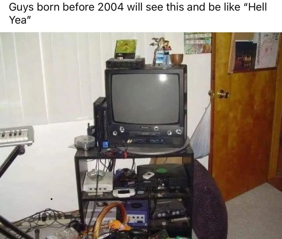 An image of a cluttered, multi-tiered TV stand filled with various old electronic devices including a CRT television, a…