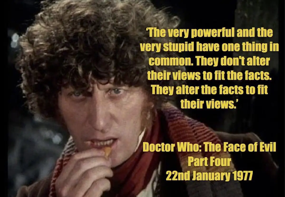 A still image of the Fourth Doctor from Doctor Who, shown with curly brown hair, wearing a red scarf and brown coat, eating…
