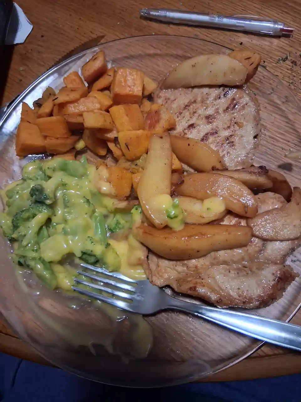 A plate of food with two pieces of grilled meat, roasted sweet potato cubes, and broccoli covered in a yellow cheese sauce…
