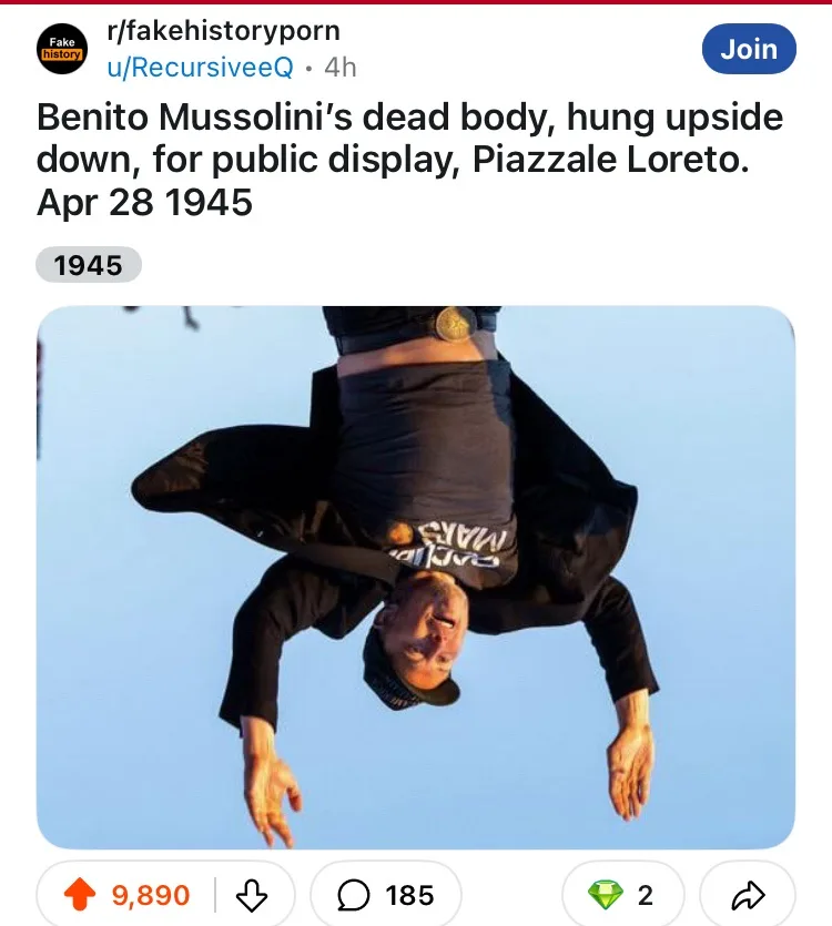 A person is hanging upside down against a clear blue sky, wearing a black jacket, black t-shirt with white text, and a black…