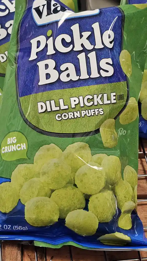 A close-up of a bag of Vlasic Pickle Balls, dill pickle flavored corn puffs, showing the green snack balls and packaging…