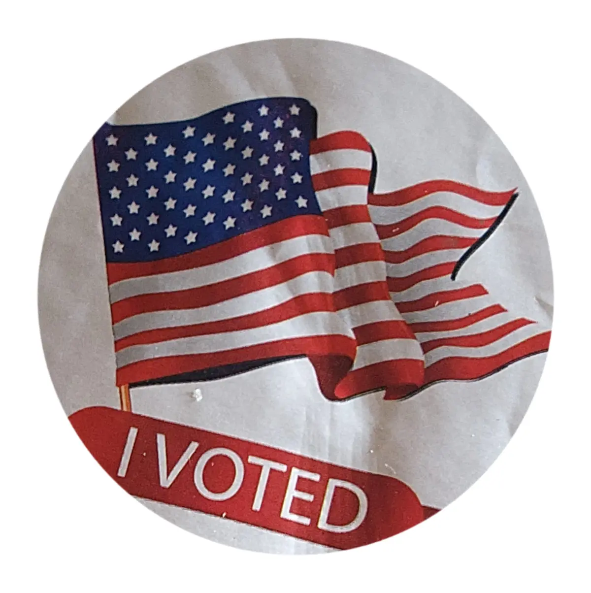 A close-up of a circular, crinkled paper sticker featuring a waving American flag with red and white stripes and a blue…