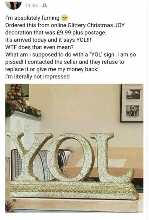 A glittery gold decorative sign spelling 'YOL' sits on a wooden stand in a living room, with a fireplace mantel and framed…