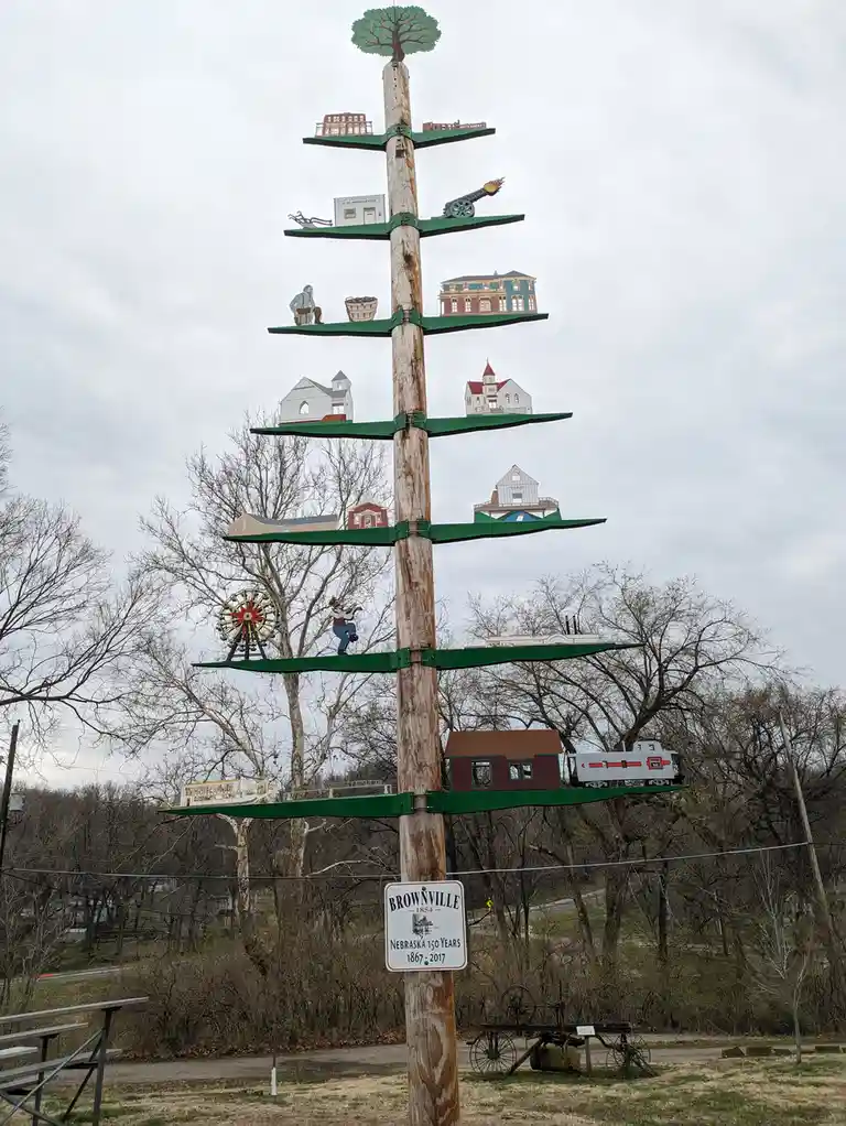 A tall wooden pole with green horizontal shelves holds miniature models of historical buildings, a cannon, a Ferris wheel, a…