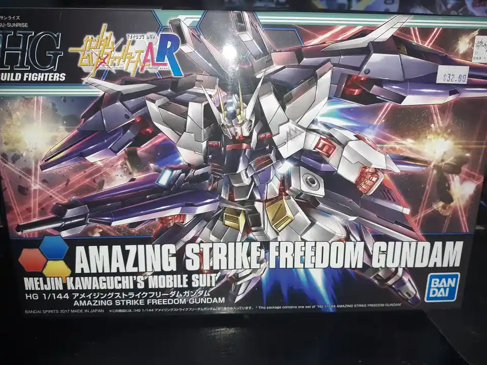 A close-up of a Bandai HG 1/144 scale model kit box for the 'Amazing Strike Freedom Gundam' from the Gundam Build Fighters…