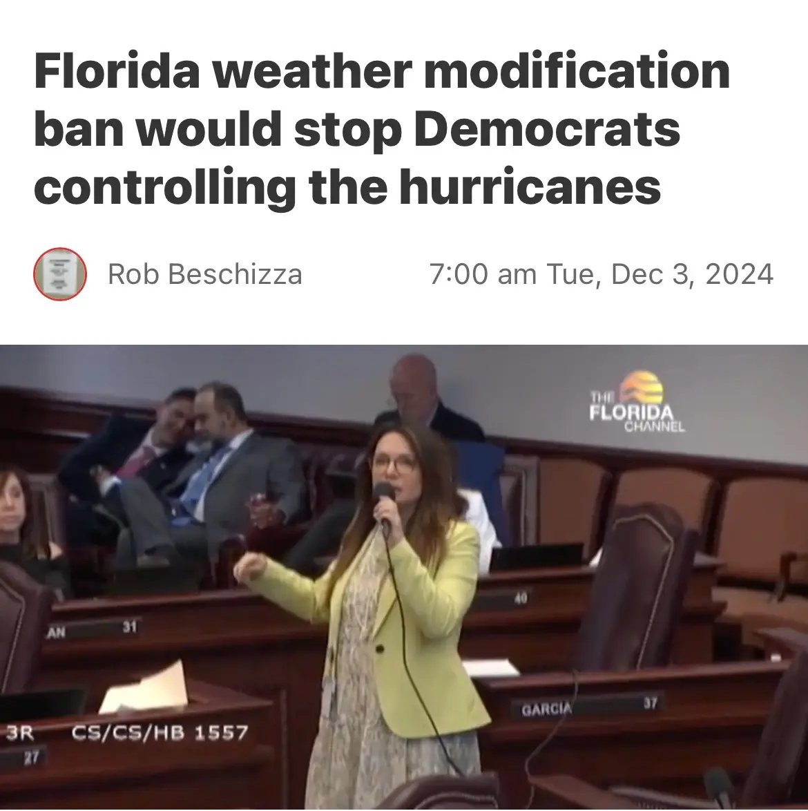 A woman in a yellow blazer speaks into a microphone in a legislative chamber, with other people seated in wooden desks…