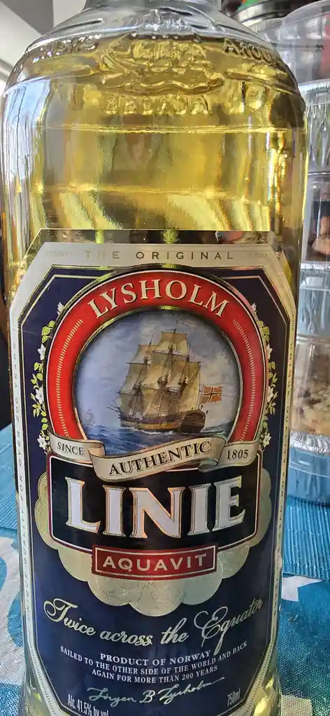A close-up of a bottle of Lysholm Linie Aquavit, featuring a label with a ship illustration and text claiming it's 'Twice…