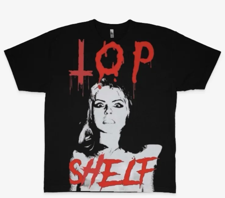 A black t-shirt displays a graphic of a woman's face in black and white, with the words 'TOP' above and 'SHELF' below in…