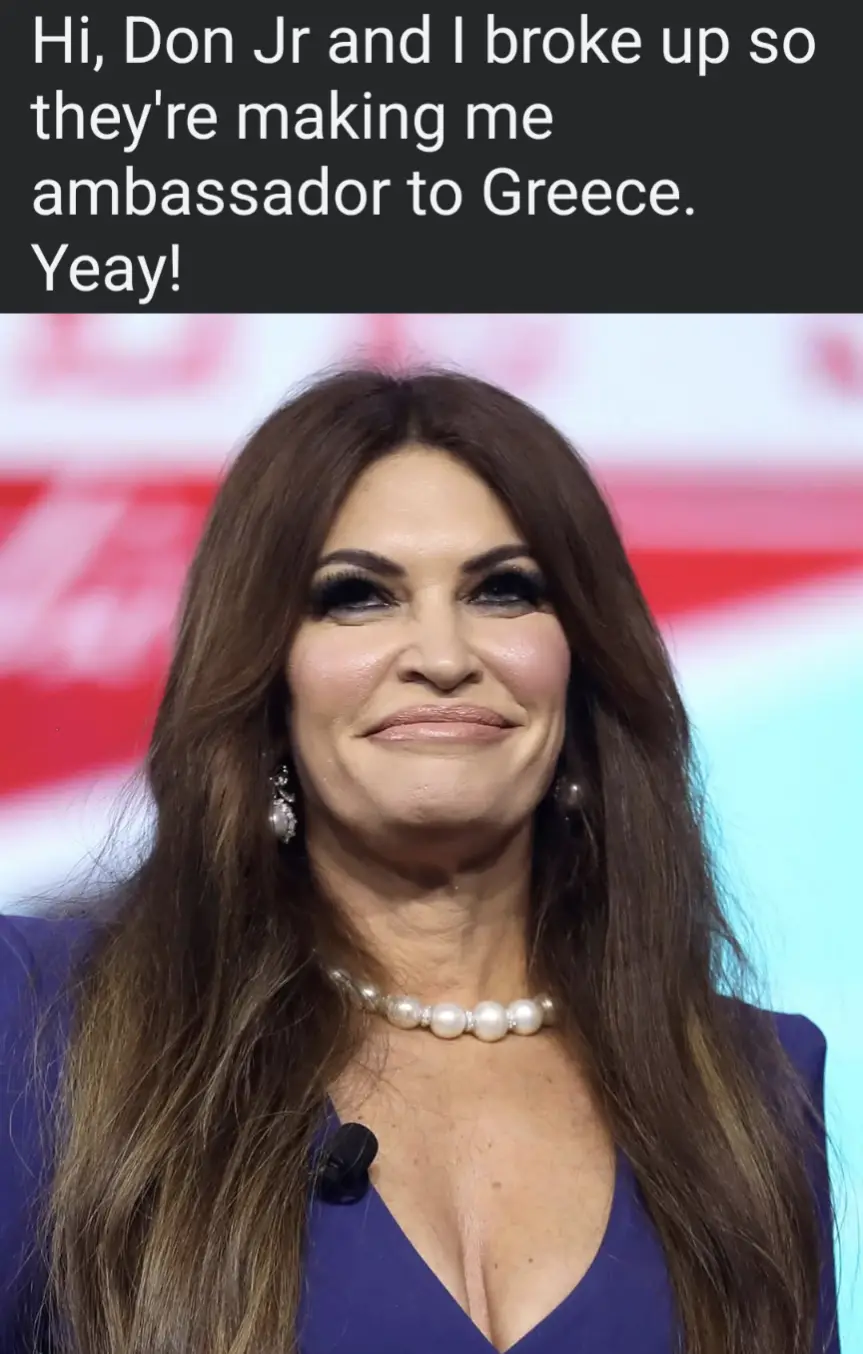 A woman with long brown hair, wearing a blue top and pearl necklace, smiles smugly while text above her reads: 'Hi, Don Jr…