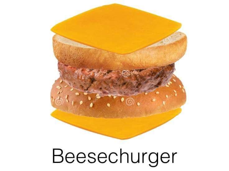 A hamburger with a beef patty, sesame seed bun, and two square slices of orange cheese, one on top of the top bun and one…