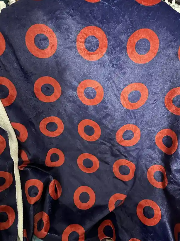 A close-up of a dark blue, textured blanket or robe with a repeating pattern of orange rings, resembling the Target store…