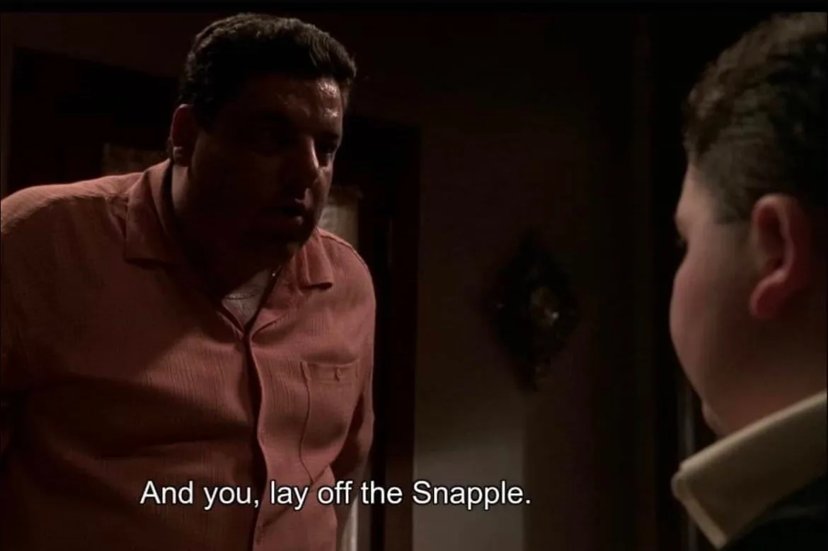 A man in a pink shirt confronts another person in a dimly lit room, with the overlaid text reading 'And you, lay off the…