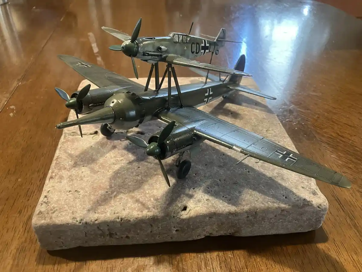 A detailed model of a German WWII aircraft, specifically a Messerschmitt Bf 109, is mounted on top of a larger model of a…