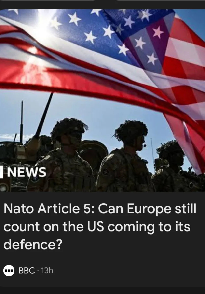The image shows silhouettes of U.S. soldiers in military gear standing under a large, waving American flag against a bright…