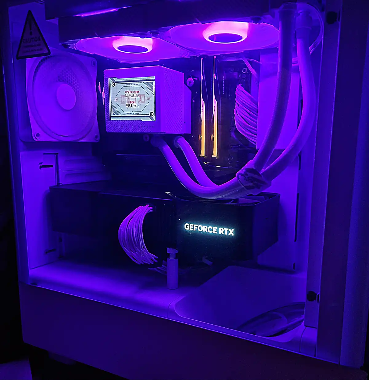 A close-up of a custom-built PC's interior bathed in purple LED lighting, showcasing a liquid cooling system with a digital…