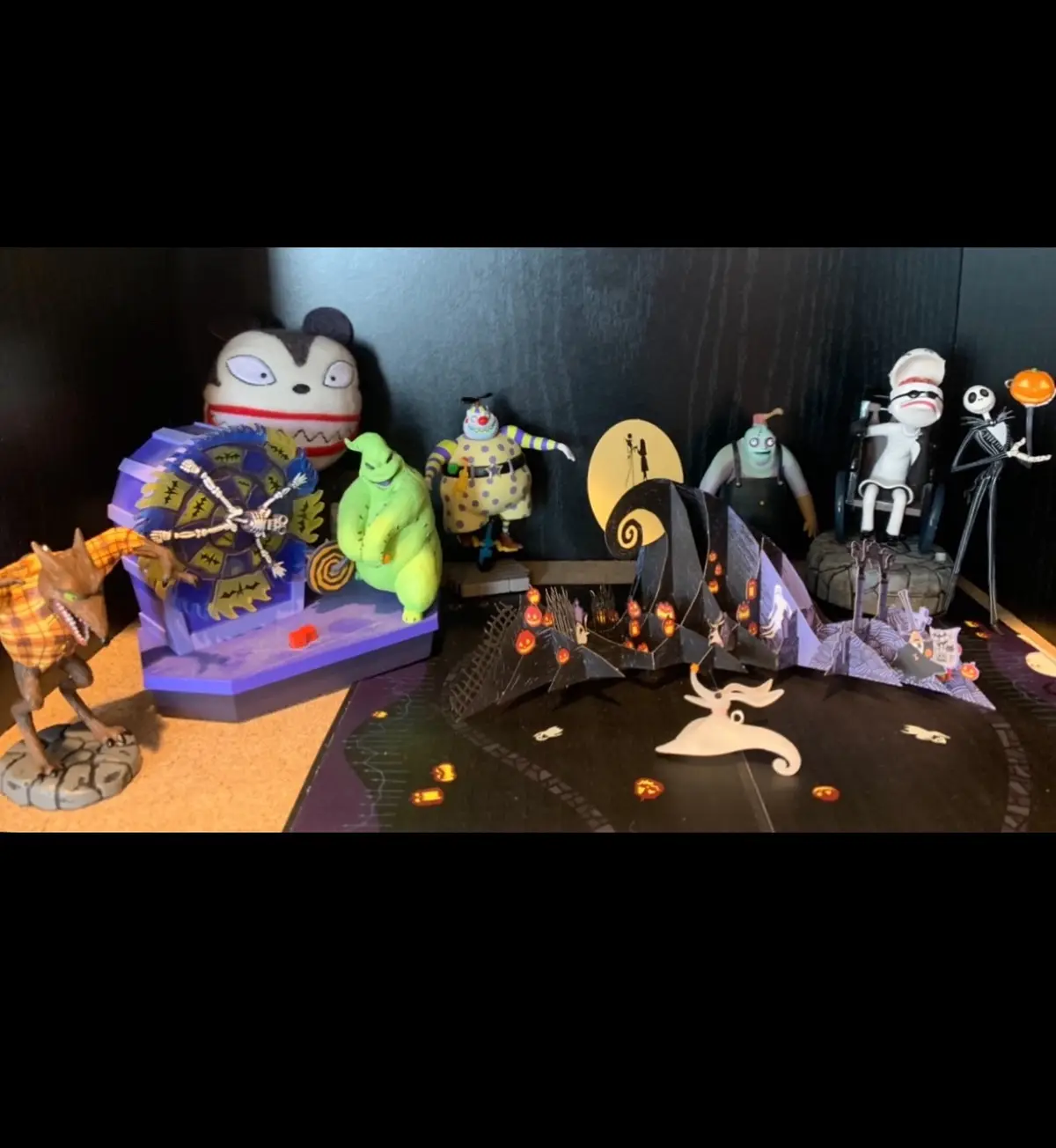 A collection of 'The Nightmare Before Christmas' figurines and dioramas arranged on a shelf, including Jack Skellington…