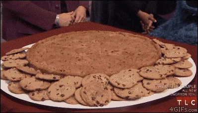 A still from a TV show shows Cookie Monster sitting at a table with a large plate of cookies. He is shown in multiple…