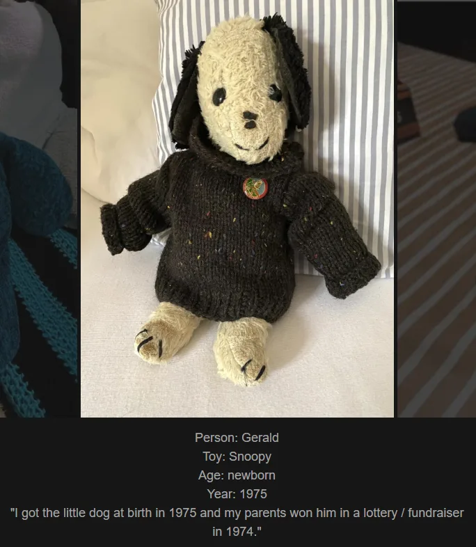 A handmade knitted plush dog resembling Snoopy sits on a bed against striped pillows, wearing a dark brown speckled sweater…