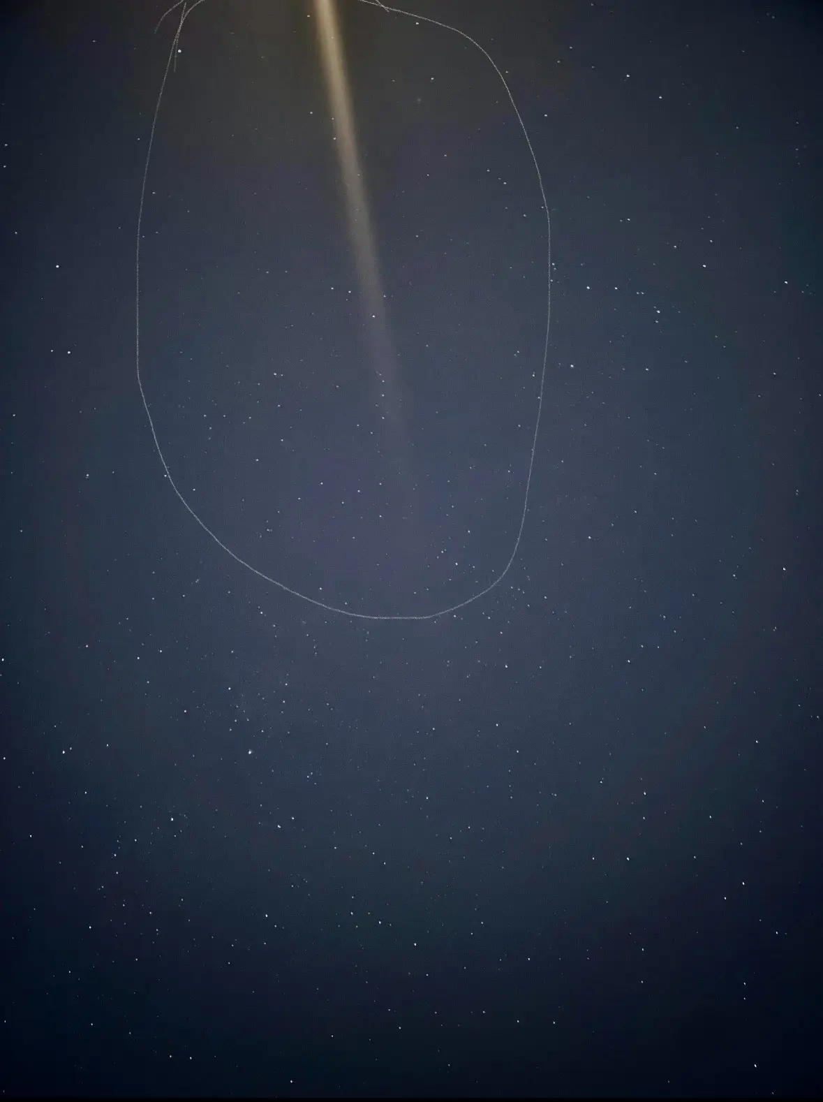 A dark night sky filled with stars, with a faint, glowing, curved line resembling a UFO drawn over it. The overlaid text…