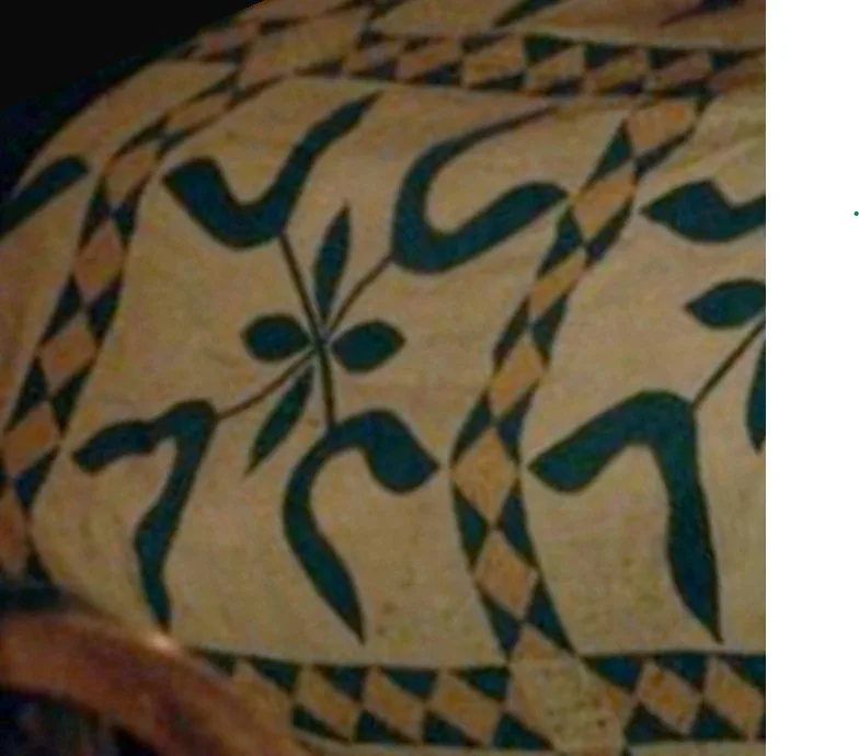 A close-up of a textile or rug with a geometric and floral pattern in beige, black, and tan. The overlaid text reads 'i'm…